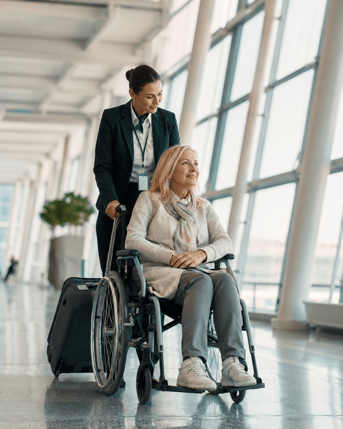 Reisender wird im Rollstuhl durch einen Flughafen begleitet als Symbol für einen organisierten Krankenrücktransport.